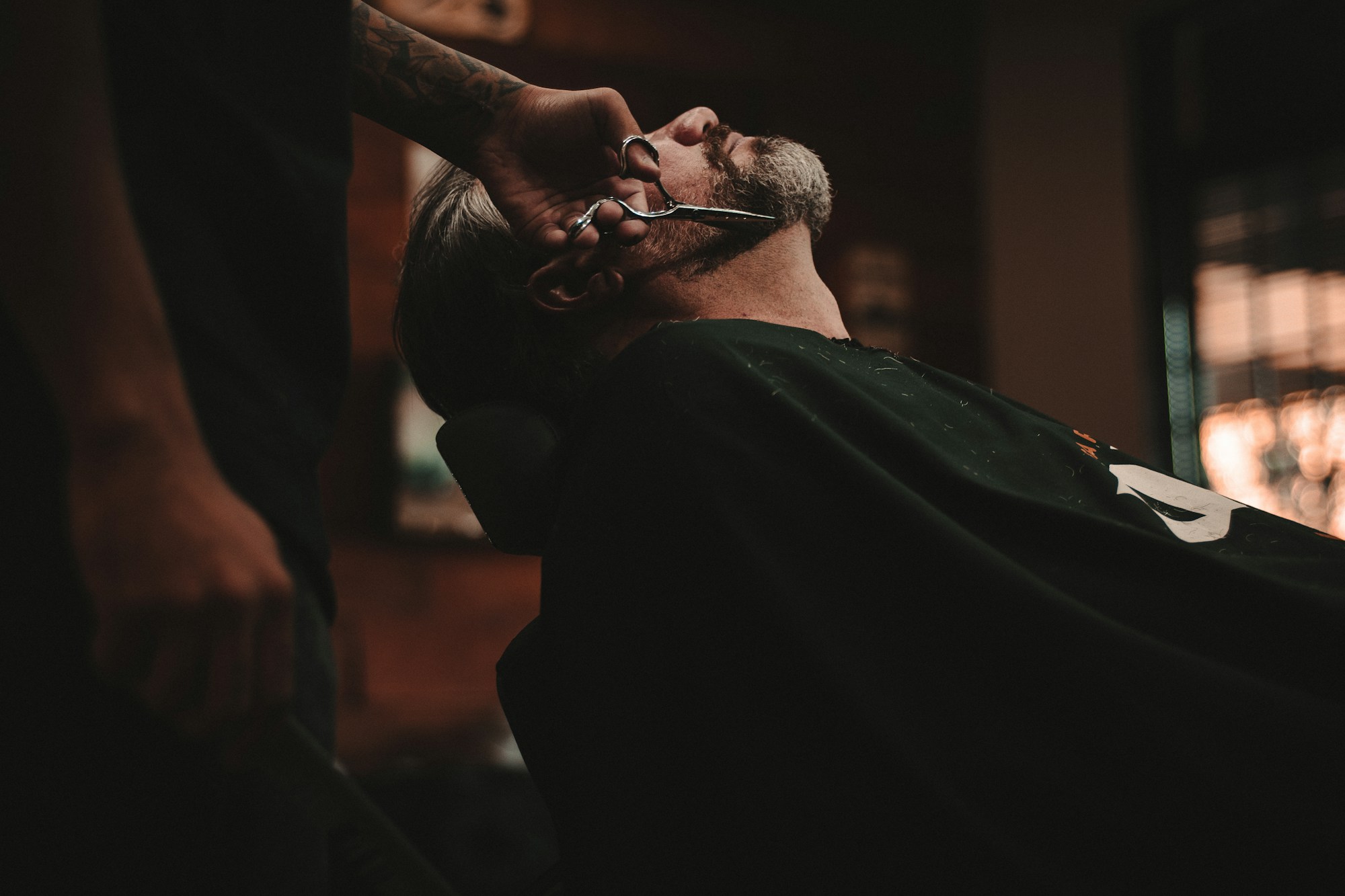 Profesional perfilando la barba de un cliente en una barbería
